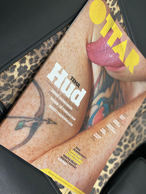 Omslaget av Ottar Tema Hud där tunga slickar en arm och en tatuering sticker fram. Ligger på en leopardmönstrad brits.