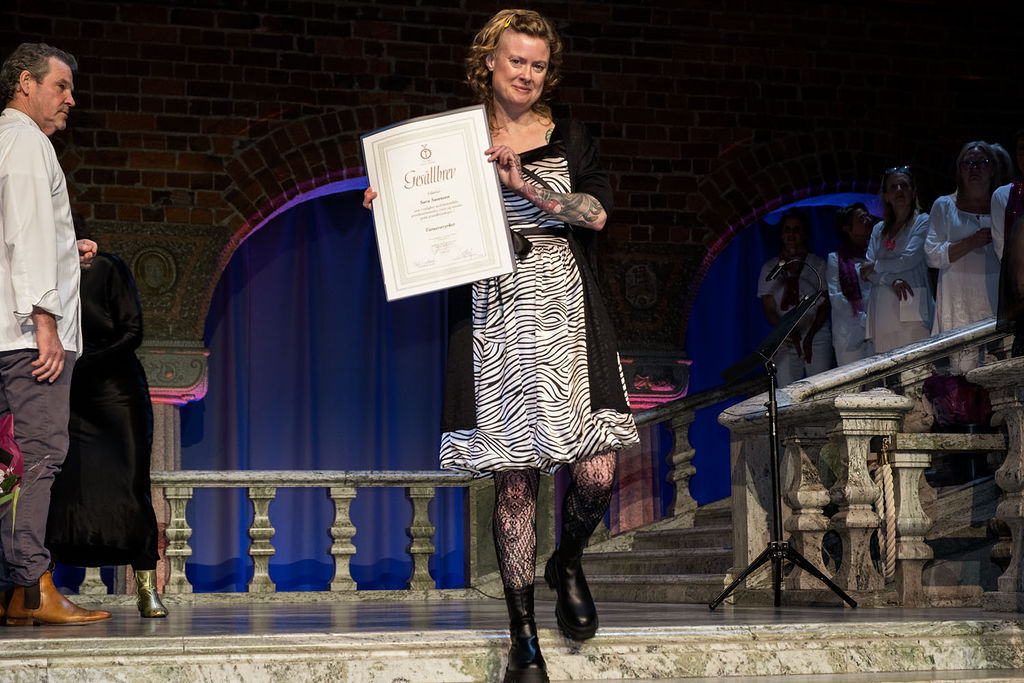 Sara Swanson decending big stairs at the city hall. She has a zebra dress, a big smile and holding her gesällbrev.