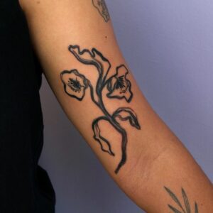 Figurative tattoo of a plant on arm, blackwork style, by tattooer Cee Burgundy.