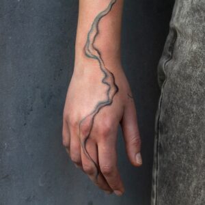 Tattoo of two lines flowing softly over arm and hand, by tattooer Cee Burgundy.
