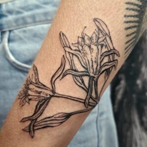 Tattoo on arm of lillies in blackwork style, by tattooer Jess Espinoza.