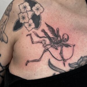 Eros skeletton with wings and arrow is tattooed over a chest.